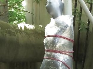 Bondaged and cocooned slave girl in the mystery garden - Full encasement fetish in zentai body bag